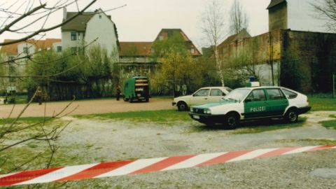Der Tatort ist abgesperrt und Polizeiwagen sind vor Ort. 