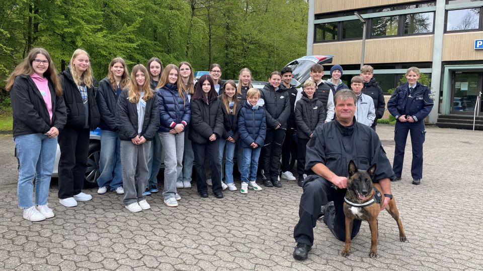 Gruppenfoto Berufsfelderkundungstag mit Diensthundführer Dirk Patzke im Vordergrund. Das Foto wurde in der Waldstraße 20 in Detmold vor dem Polizeigebäude angefertigt.